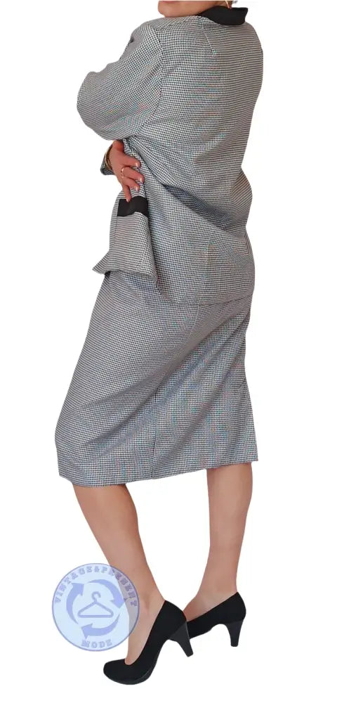 Frau in gebrauchtem Pepita Kostüm: grauer Blazer und Rock mit schwarzem Kragen